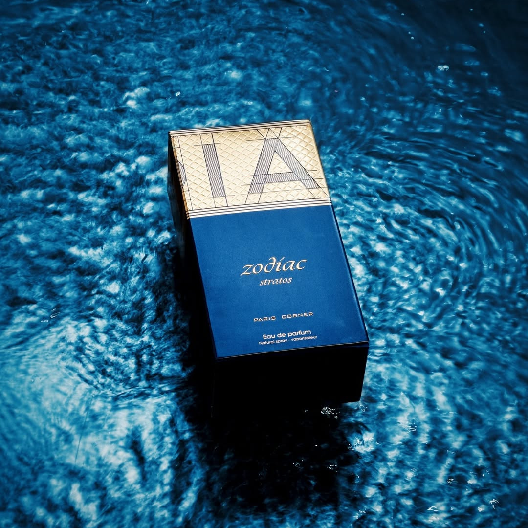 The Zodiac Stratos 100ml EDP by Paris Corner is immersed in rippling blue water, creating a luxurious and tranquil scene. This dark blue perfume box features golden accents, hinting at the earthy notes inside.