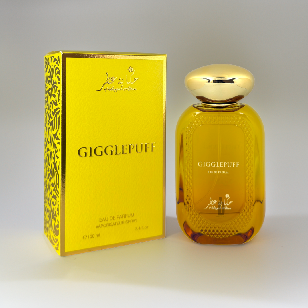 The bright yellow Gigglepuff 100ml EDP by Hekayat Attar features a matching bottle with a gold cap, offering an enticing gourmand-floral fruity fragrance. Decorative black designs hint at Italian lemon and coconut cream notes against a neutral gray background.