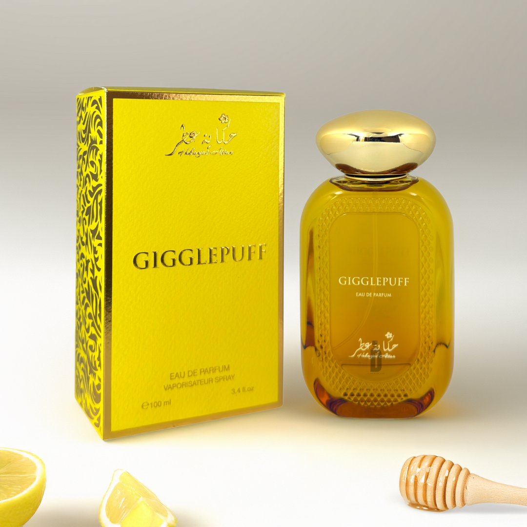 A yellow box and matching "Gigglepuff 100ml EDP - Hekayat Attar" bottle feature a floral design, Italian lemon slices, and a honey dipper, highlighting its Gourmand-Floral Fruity scent with hints of coconut cream accord for added luxury.