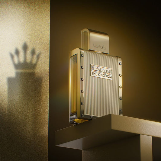 A golden perfume bottle labeled "The Kingdom Men 100ml EDP - Lattafa" by the brand Lattafa sits on a pedestal, casting a crown-shaped shadow on the textured wall behind. The scene is illuminated by warm light, enriched with notes of vanilla, creating a regal and luxurious ambiance.