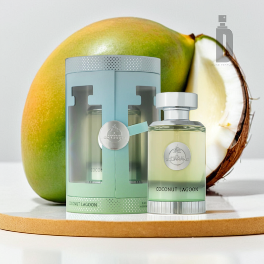 In a bright and minimalistic setting, a bottle of Coconut Lagoon 100ml EDP by Paris Corner, designed with a sleek glass finish, is showcased beside its coordinating decorative box. A halved coconut in the background subtly suggests the inspiration for the fragrance's scent.