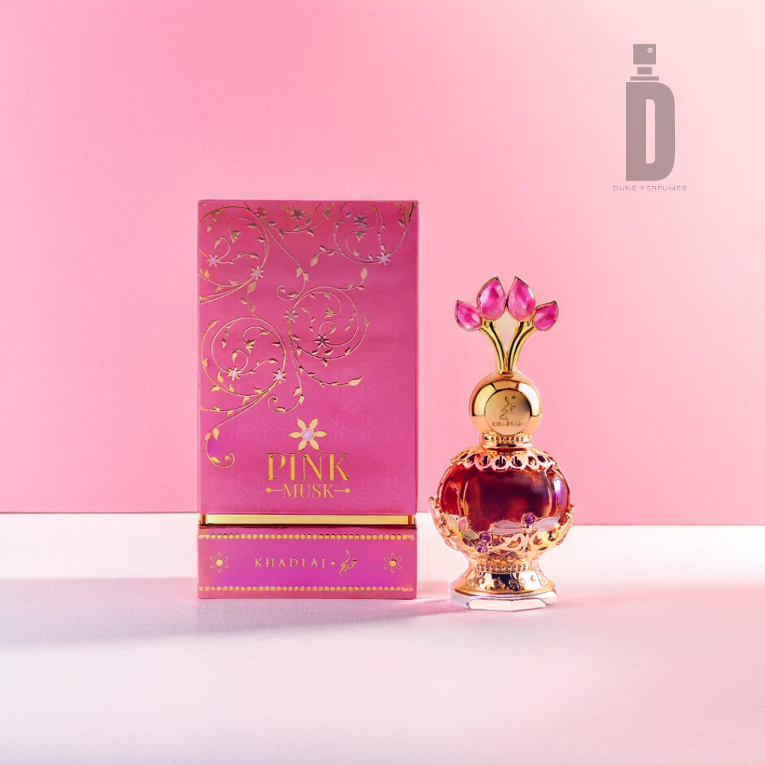 A Khadlaj Pink Musk 20ml Perfume Oil bottle, featuring a gold and pink design, sits beside its intricately designed pink box labeled with the product name. The backdrop is a gradient of soft pink shades, beautifully embodying the enchanting floral heart notes enriched by the exquisite fragrance oil within.