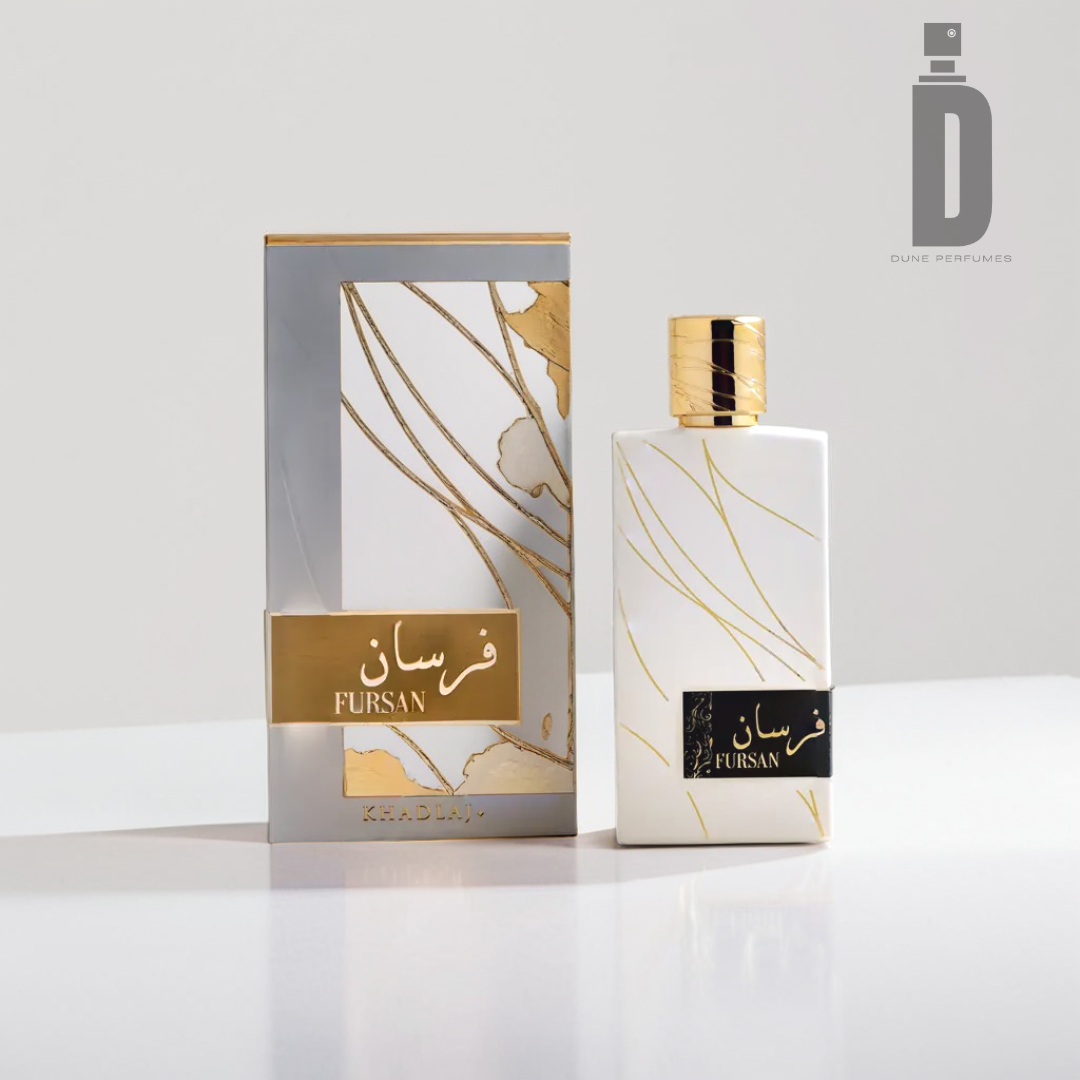 A white and gold perfume box and bottle labeled "Fursan White 100ml EDP - Khadlaj" are elegantly placed on a white surface, emanating a luxurious fragrance. The design includes refined gold lines and accents that suggest a gentle vanilla cedarwood aroma. The Khadlaj brand logo is seen in the top right corner.