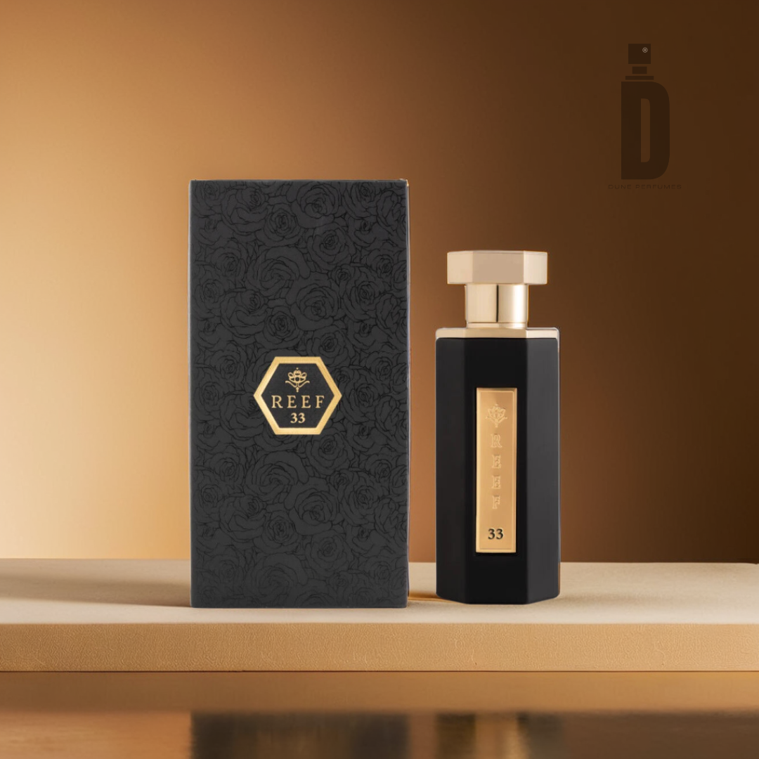 A luxurious Reef 33 black 100ml EDP bottle and matching box lie on a beige surface, exuding luxury. The hexagonal "Reef 33" logo features prominently, set against a warm brown gradient that captures rosemary and woody oud's essence.