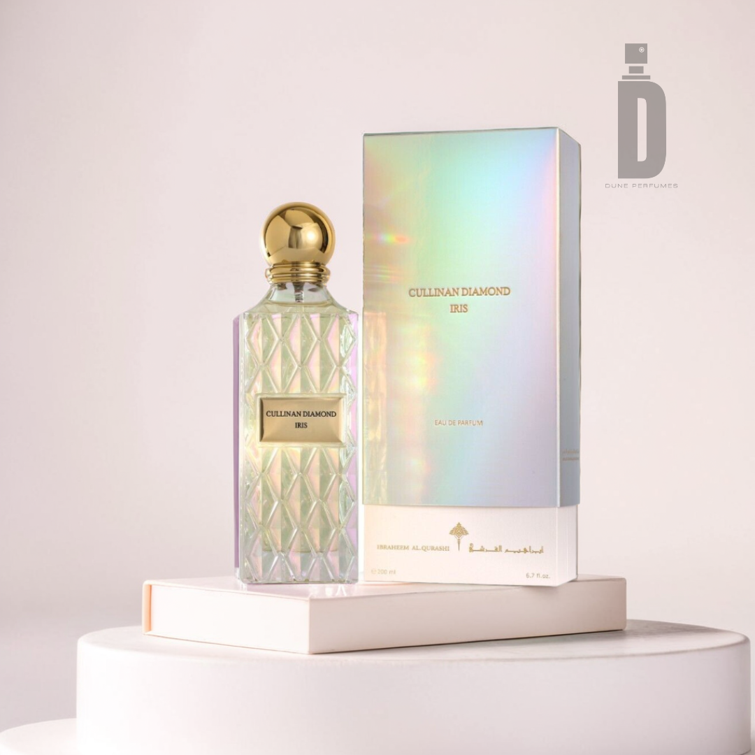 A luxurious Cullinan Diamond Iris 200ml EDP bottle from Ibrahim Al Qurashi, featuring a diamond pattern and gold cap, is elegantly paired with its iridescent box. Both sit on a white circular platform, radiating opulence against the minimalist backdrop.