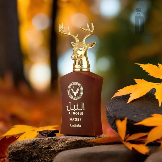 A perfume bottle with a brown label and a gold deer head cap is positioned on rocks surrounded by autumn leaves. The label reads "Al Noble Wazeer 100ml EDP - Lattafa" in English and Arabic, hinting at the regal scent within. The background features a blurred image of a fall scene with warm colors, evoking luxury fragrance vibes.