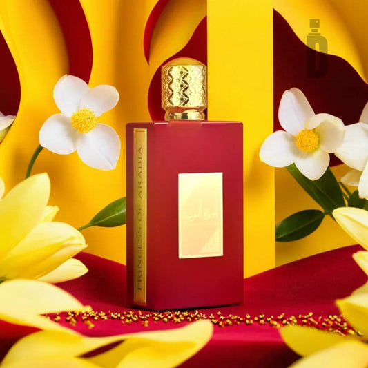 A red perfume bottle with a gold cap, bearing the label "Ameerat Al Arab 100ml EDP - Asdaaf" by Lattafa, is surrounded by yellow flowers and petals on a vibrant red surface. The backdrop features bright yellow and red colors, while decorative golden beads scattered around the base of the bottle hint at notes of exotic oud within.