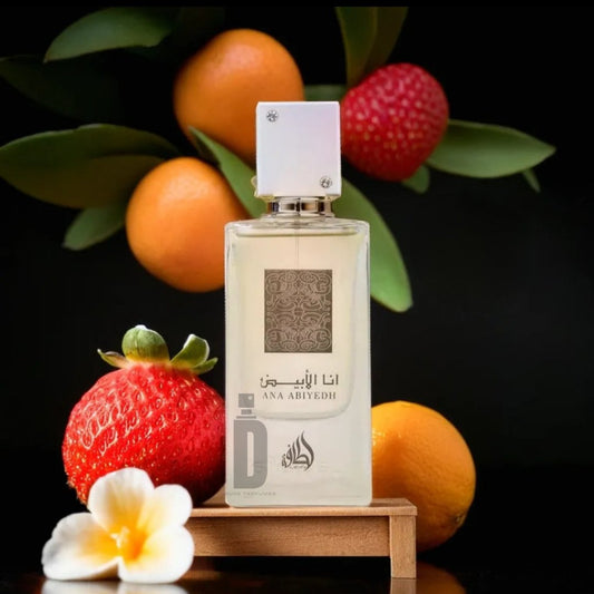 A 60ml bottle of "Ana Abiyedh EDP" by Lattafa is showcased against a backdrop of botanical elements. The display features whole strawberries, oranges, green leaves, and a white flower arranged on a wooden stand, creating an ambiance of fresh elegance and sophistication.