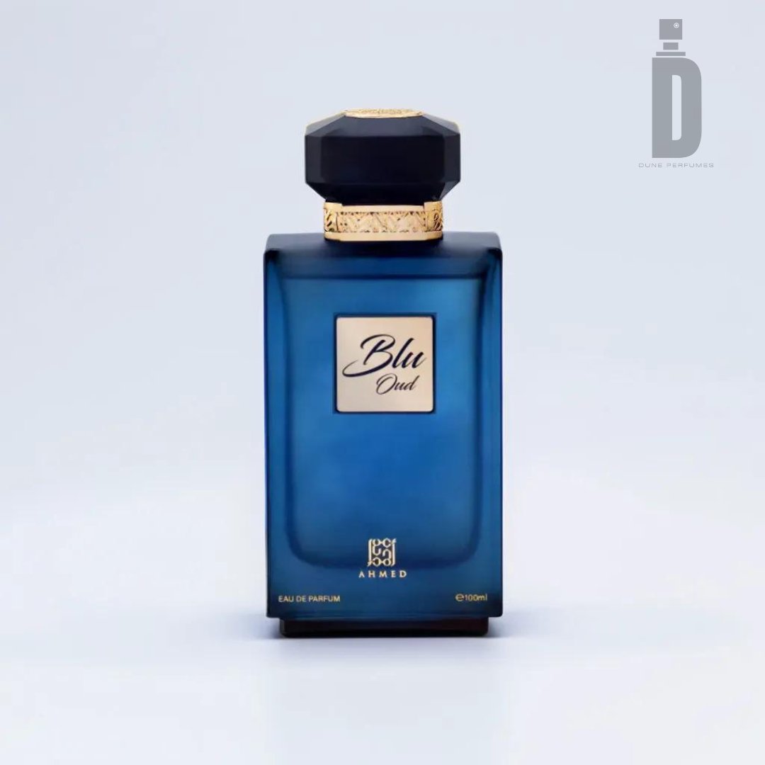 A 100ml blue glass bottle of "Blu Oud" Eau de Parfum by Ahmed Al Maghribi, featuring a gold cap with an intricate design and a small black label on the front. The logo of Dune Parfums is displayed in the top right corner, signifying its sophisticated fragrance.