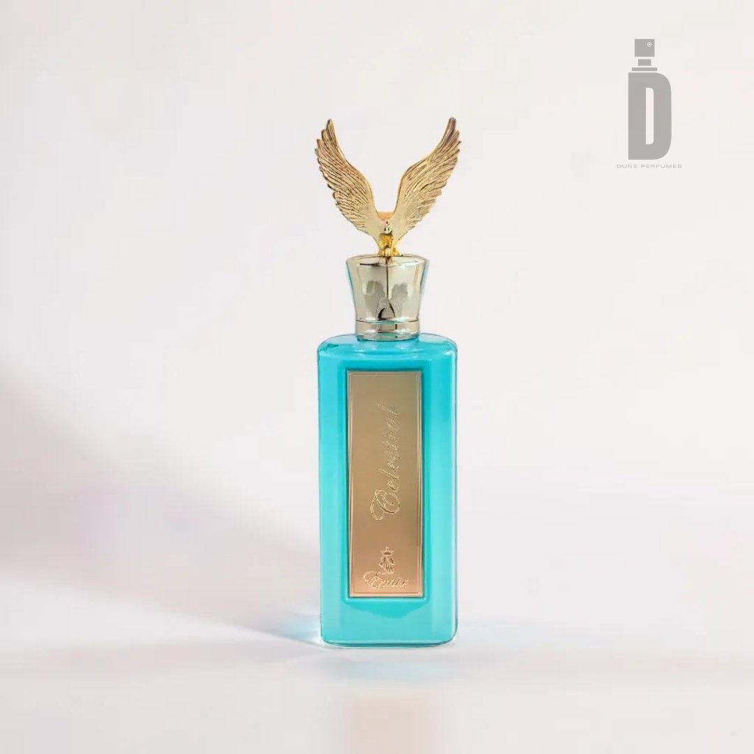 This perfume bottle, known as Celestial 100ml EDP - Emir by Paris Corner, features a turquoise hue with a gold rectangular label and a golden cap topped with an eagle-shaped ornament. The bottle, radiating an ethereal blend, is elegantly displayed against a plain white background.