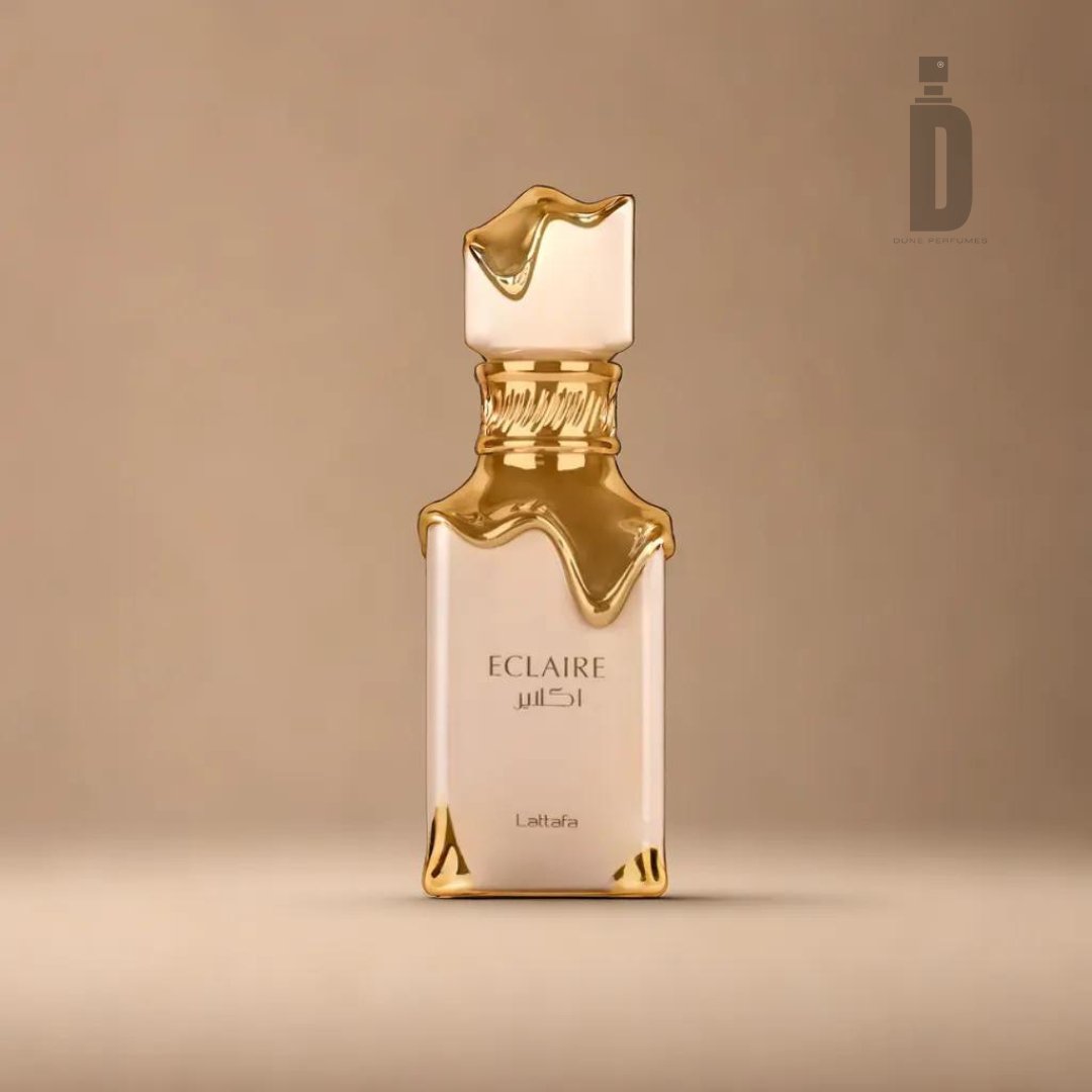 A 100ml bottle of Eclaire Eau de Parfum by Lattafa, featuring a sleek rectangular design adorned with a drizzled gold effect on the top and cap, sits against a warm beige background, evoking images of caramel milk and vanilla praline indulgence.