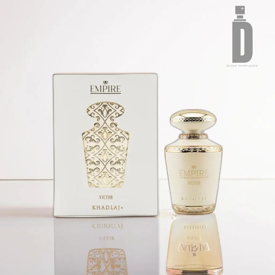 An Empire Victor 100ml EDP by Khadlaj is placed next to its white and gold ornate packaging box on a reflective surface. The luxurious fragrance gleams under the light, while the Dune Perfumes logo is visible in the top right corner of the image.