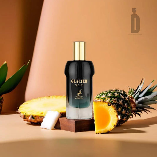 A bottle of Glacier Bold 100ml EDP from Maison Alhambra is displayed against a beige background. The dark bottle, featuring white lettering and a gold cap, is surrounded by whole, halved, and sliced pineapples. Subtle hints of bergamot enhance the tropical essence of the scene.