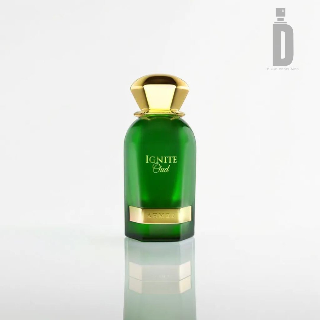 A green bottle of perfume labeled "Ignite Oud 60ml EDP - Ahmed Al Maghribi" with a gold cap and base, sitting on a reflective white surface. The logo and name "Ahmed Al Maghribi" appear in gray in the upper-right corner, hinting at luxurious notes of Oud fragrance intertwined with hints of Sandalwood Musk.