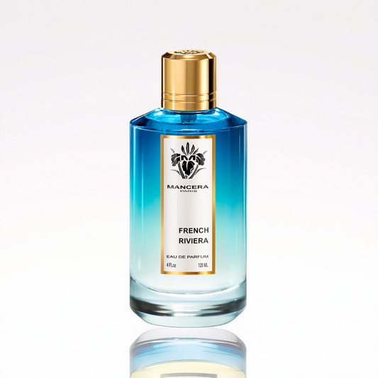 A cylindrical bottle of "French Riviera 120ml EDP" by Mancera, evocative of a coastal getaway, features a gradient blue design with a gold cap and stands upright on a reflective surface.