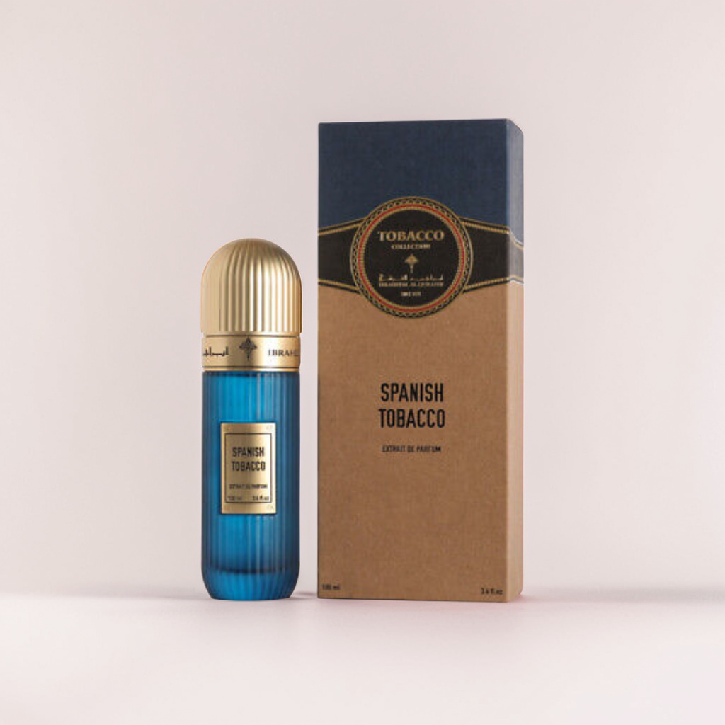 A blue glass perfume bottle with a ribbed golden cap, labeled "Spanish Tobacco," is paired with its rectangular box. The brown box, topped in navy blue, complements the luxurious amber scent of this 100ml EDP by Ibrahim Al Qurashi.