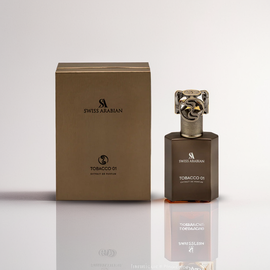 A 50ml bottle of Swiss Arabian Tobacco 01 perfume with an intricate cap sits beside its matching rectangular box. Both the bottle and box feature a rich golden-brown hue, exuding a complex, smoky scent as they reflect light on a white surface.