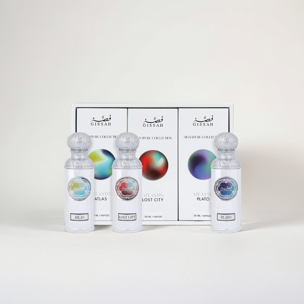 Three elegant bottles labeled Atlas, Lost City, and Plato are displayed in front of a white box with colorful circular designs. The box features "Gissah" and "Signature Collection," offering an ambery scent with captivating floriental notes.