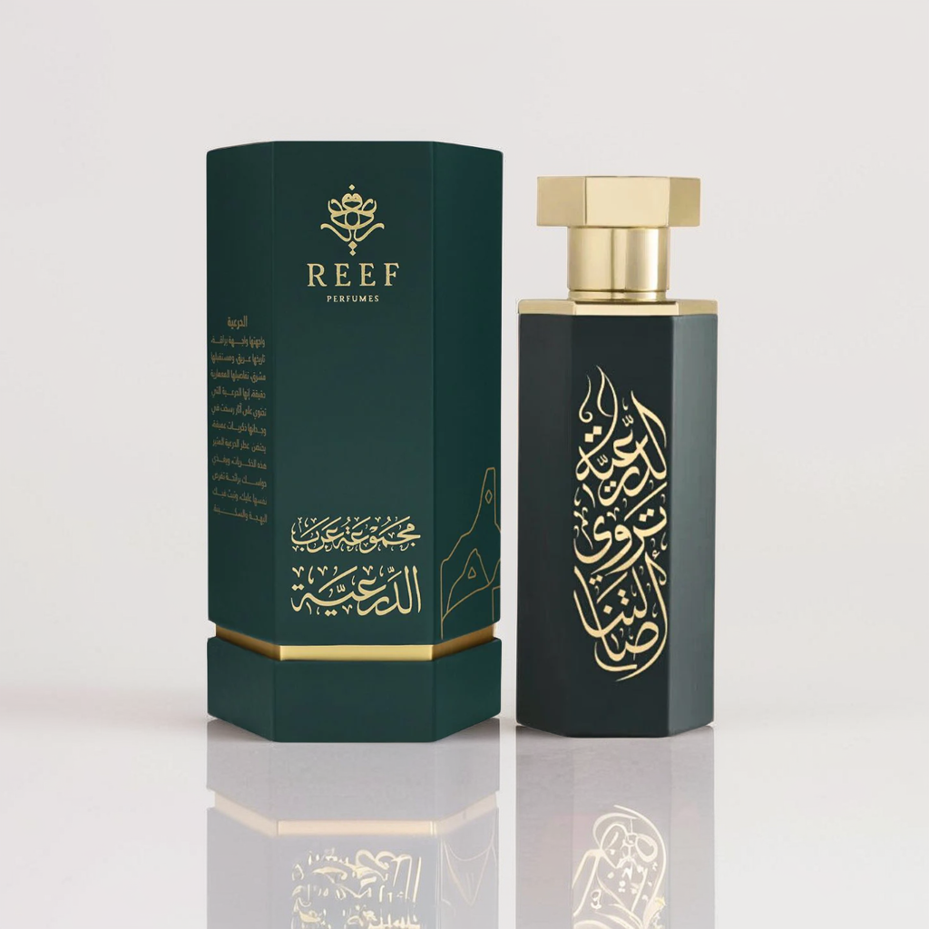 The Diriyah 100ml EDP by Reef features a luxurious dark green box and cylindrical bottle with gold accents and elegant Arabic calligraphy. The design hints at rich agarwood and saffron notes, while the box proudly showcases the "Reef Perfumes" logo on a dark green backdrop.