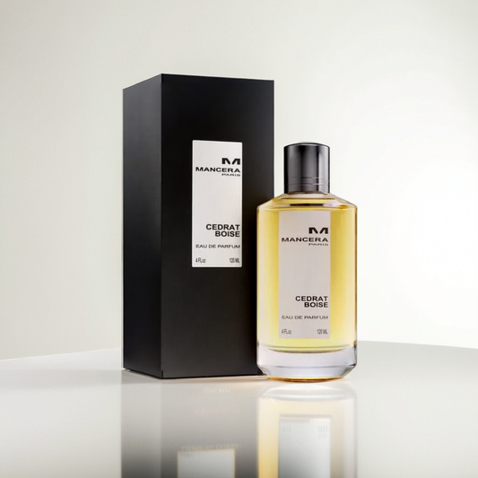 A bottle of Cedrat Boise 120ml EDP by Mancera, celebrated for its mesmerizing citrus aroma, is placed beside its elegant black packaging on a reflective surface. The fragrance is contained in a transparent bottle with a black cap, featuring the brand name Mancera prominently on both the box and the bottle.