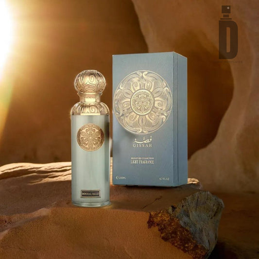 The Imperial Valley 200ml EDP by Gissah and its luxurious box are displayed on a rock under sunlight. The translucent bottle, adorned with an ornate gold-colored cap and label, is accompanied by a matching box featuring intricate golden designs and Arabic text. This Amber Woody fragrance stands out beautifully against the warm-toned rocks of Imperial Valley.