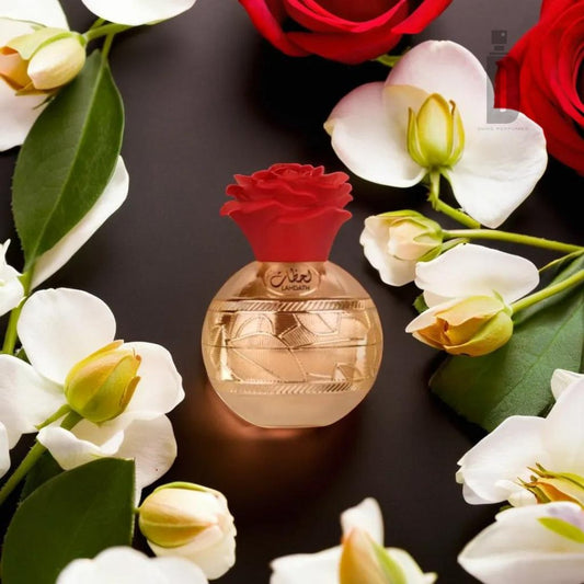 The Lahdath 80ml EDP by Lattafa features a beige bottle adorned with a golden pattern and script, topped with a red rose-shaped cap. It is surrounded by white flowers and green leaves, exuding timeless elegance. The background, filled with more red and white flowers, creates a Mediterranean garden ambiance.