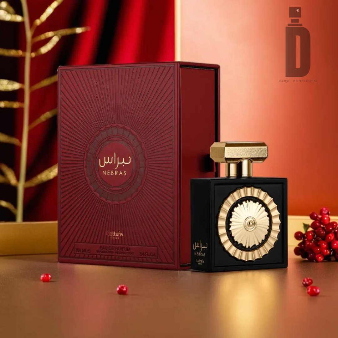 A luxurious perfume bottle labeled "Nebras 100ml EDP - Lattafa Pride" from Lattafa sits beside its ornate red and gold box, emanating a sensual allure. The background is elegantly decorated with red curtains, golden leaves, and red berries, creating a festive and opulent setting. The Dune Refineries logo is visible in the upper right corner.