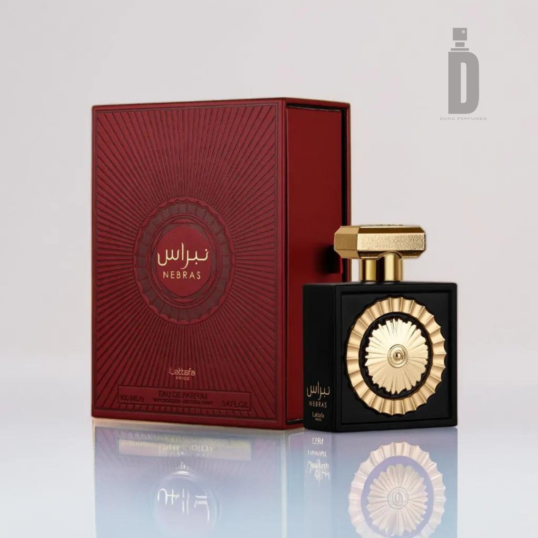 Introducing the Nebras 100ml EDP - Lattafa Pride by Lattafa, a luxurious fragrance set featuring an elegant black bottle adorned with a gold floral emblem and cap. It comes in a matching red and gold ornate box with “Nebras” beautifully written in both Arabic and English. This packaging exudes elegance, sophistication, and sensual allure, designed to ignite romance.