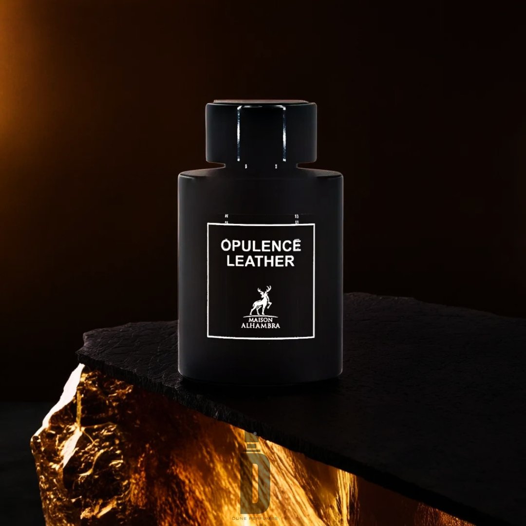 A black, cylindrical perfume bottle labeled "Opulence Leather" from Maison Al Hambra is set against a dark background. The bottle is placed on a dark, glossy surface with a textured, gold section in the foreground, exuding sophistication and crafting an aura of luxurious fragrance.