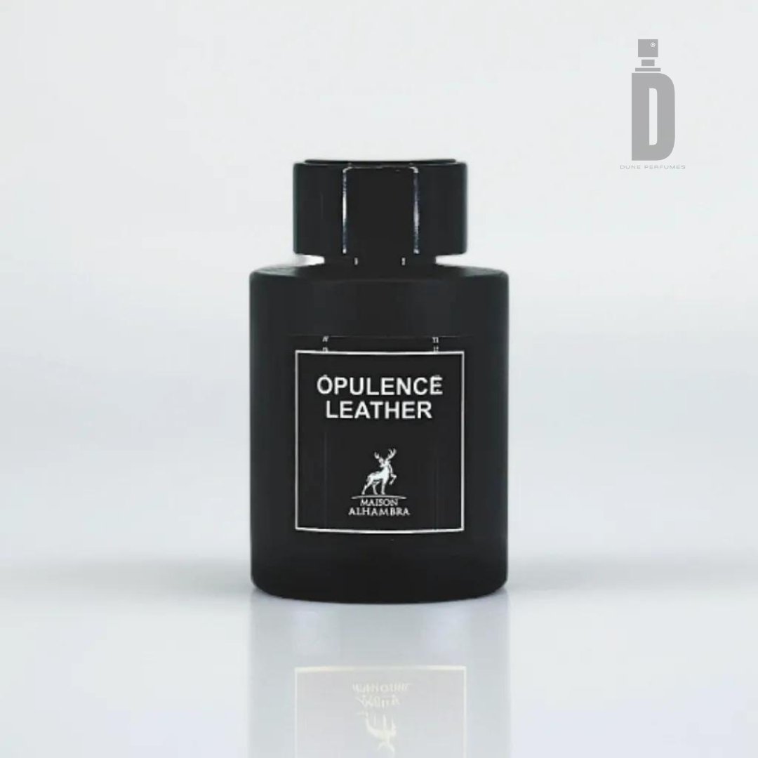 A black perfume bottle with bold text reading "OPULENCE LEATHER" on the label exudes sophistication. Beneath the text, a small deer logo and the brand name "MAISON AL HAMRA" are displayed. The cylindrical shape and matching black cap add to its allure, set against a white, minimalistic background, highlighting this luxury fragrance from Maison Alhambra's Opulence Leather (previously Amber & Leather) 100ml EDP collection.