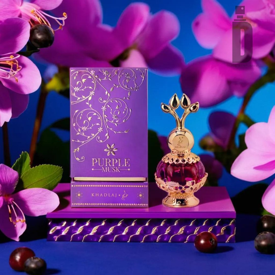 A luxurious perfume bottle with an ornate gold design sits next to a matching purple and gold box labeled "Purple Musk 20ml Perfume Oil - Khadlaj." The items are placed on a purple platform adorned with purple flowers and black olives in the background, evoking the rich, Fruity Accord of this exquisite perfume oil by Khadlaj.