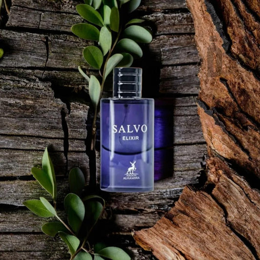 A bottle of Salvo Elixir 60ml EDP - Maison Alhambra, with its sophisticated purple liquid, stands upright on a wooden surface surrounded by leafy green branches. The background features textures of rough bark and weathered wood, enhancing the elegance of this refined fragrance from Maison Al Hambra.