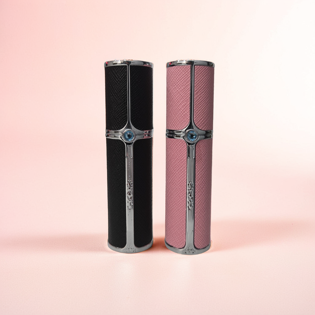 Two 5ml Travel sprays from Dune Perfumes stand upright on a soft pink background. One is black, and the other is pink, both featuring intricate silver detailing.