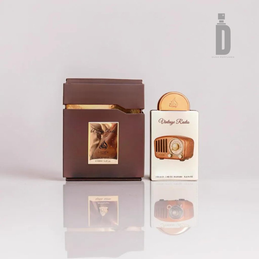 A brown, rectangular perfume bottle with golden accents stands next to its matching box. The box has an image of an eagle and Arabic text. Beside it is a smaller white box labeled "Vintage Radio 100ml EDP - Lattafa," featuring an illustration of a vintage radio that evokes a sense of nostalgia.