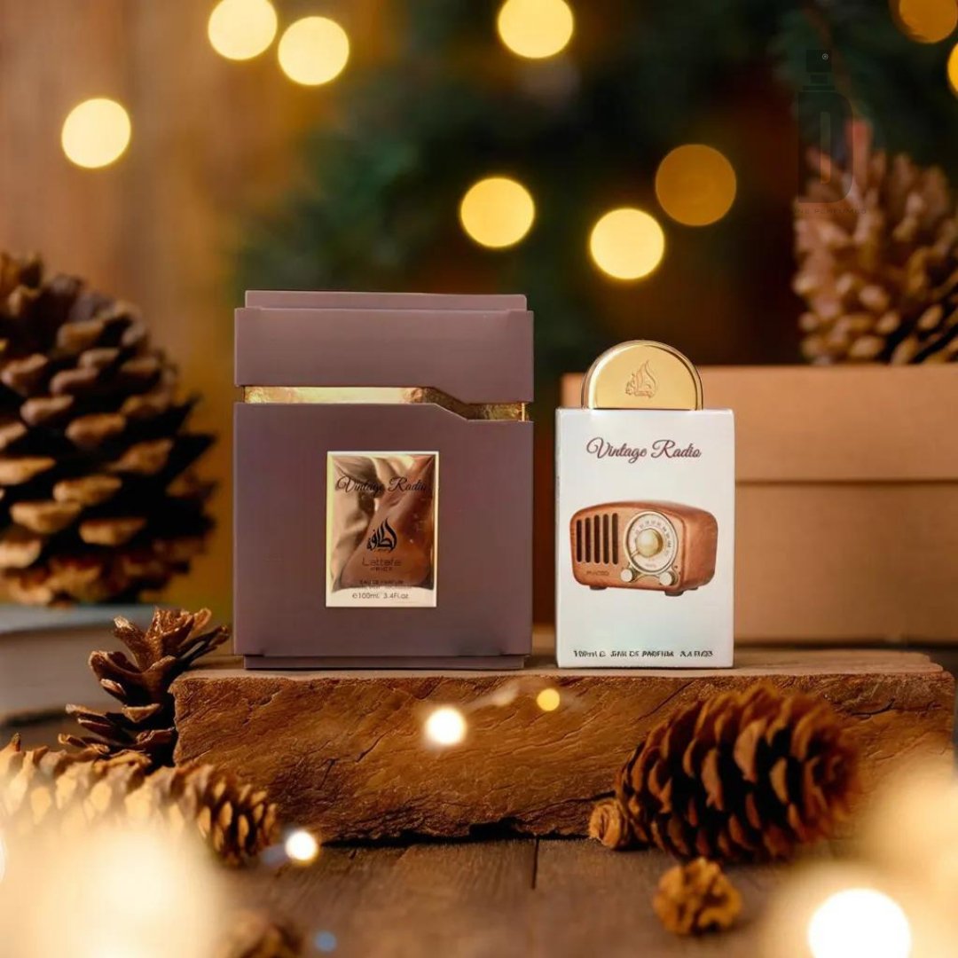 A festive arrangement features the Vintage Radio 100ml EDP by Lattafa, housed in a brown and gold box with a vintage radio design, displayed on a wooden surface and surrounded by pinecones and twinkling fairy lights. The nostalgic packaging hints at this holiday-themed fragrance product being perfect for the season.