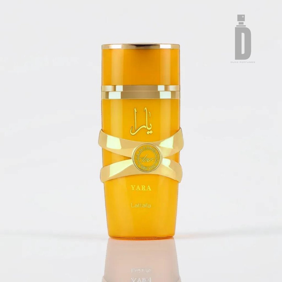 A bottle of Yara Tous 100ml EDP by Lattafa is displayed against a white background. The vibrant yellow bottle, adorned with a gleaming gold cap and gold accents, exudes an exotic allure. The Lattafa logo and the "Yara" name are prominently featured on the front, suggesting a captivating tropical fragrance inside.